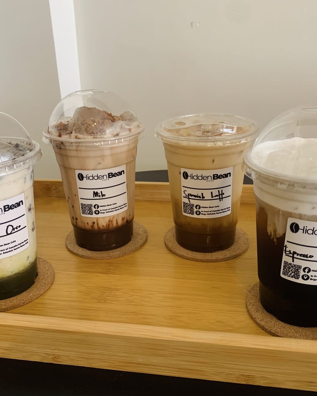 Four iced drinks lined up on a wooden tray